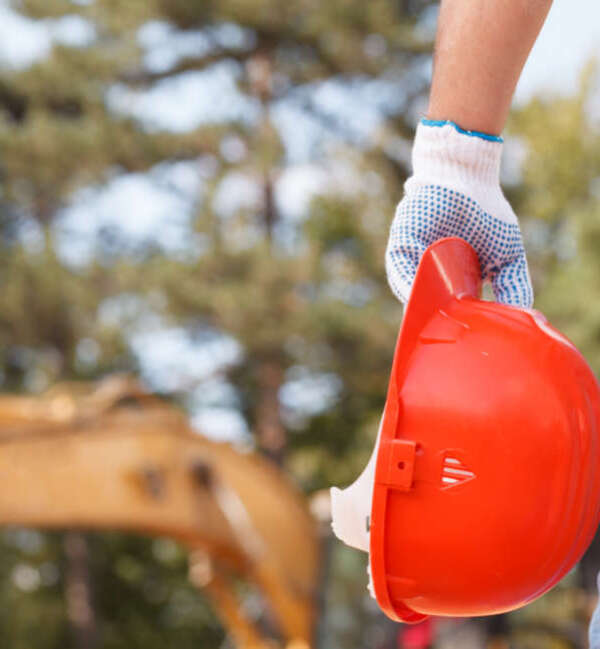 closeup of engineer holding orange helmet on construction site outdoors